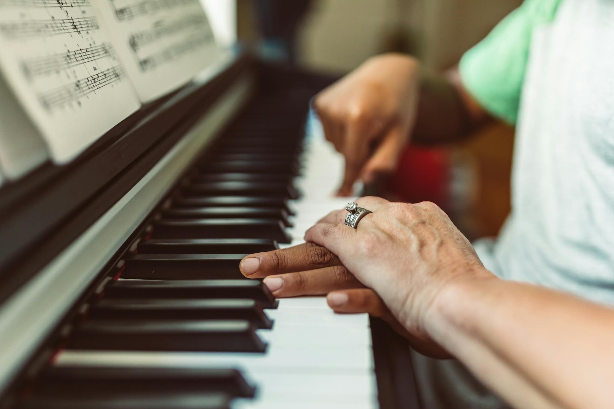 A close-up view of hands playing a piano keyboard, symbolizing music education and connection.