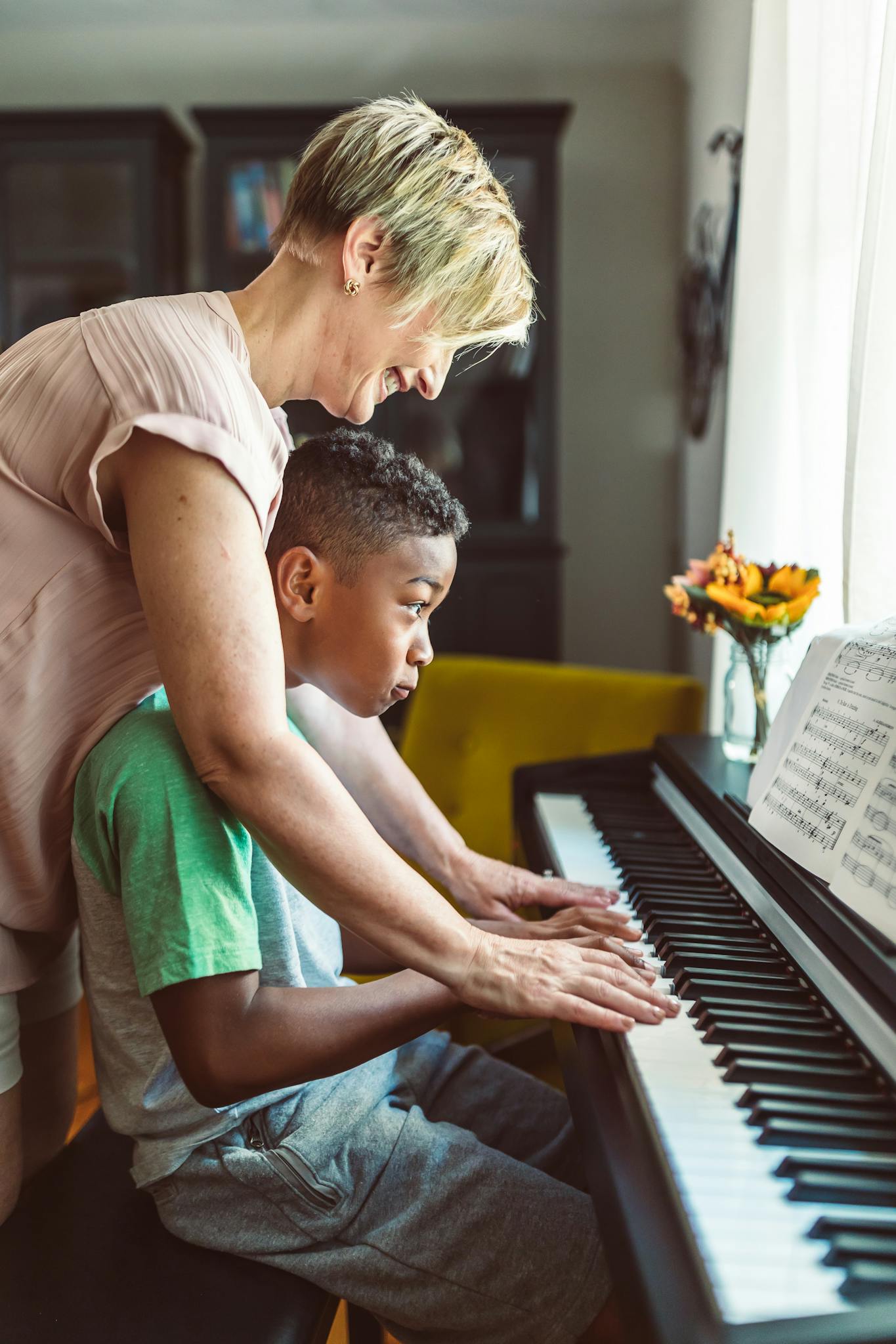 A mother teaches her son piano in a cozy home setting, showcasing bonding and musical education.