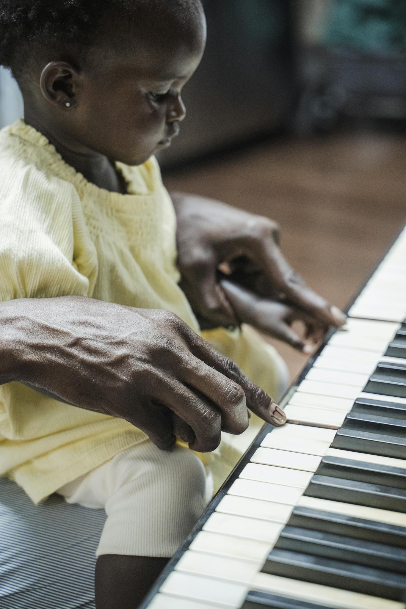 A father guides his young daughter in playing the piano, fostering musical learning.